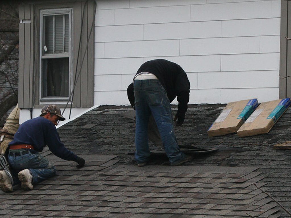 Roofers laying a new layer of shingles during a roof replacement